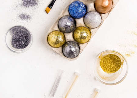 Easter holiday. DIY eggs in sequins and glue on a white background.の写真素材