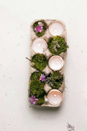 DIY Easter. Candlestick from eggshells on a white background with flowers and moss. Vertical photo. Copy spaceの写真素材