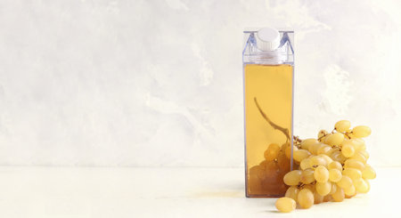 Mock up bottles with grape juice on a gray background. Nearby is a bunch of ripe grapes. Banner. Copy spaceの写真素材