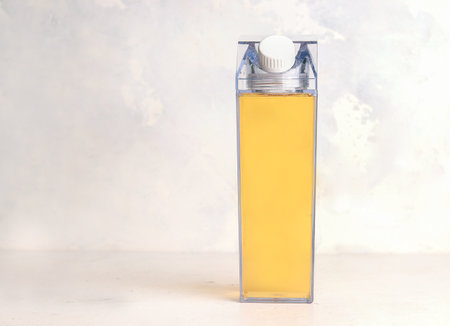 Yellow juice in a bottle on a gray background. Copy space. Mock upの写真素材