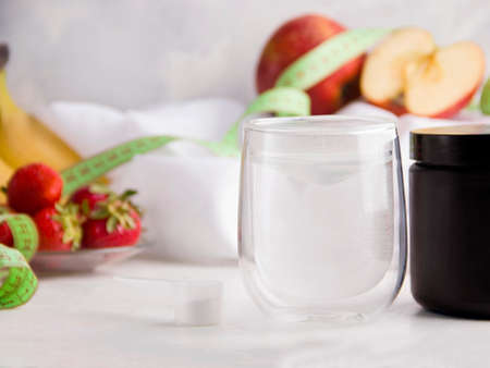 White drink for people doing sports on a white background next to different fruitsの写真素材