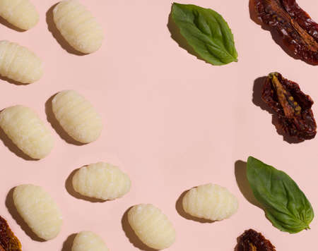 gnocchi on a pink background next to tomato and basil. copy spaceの写真素材