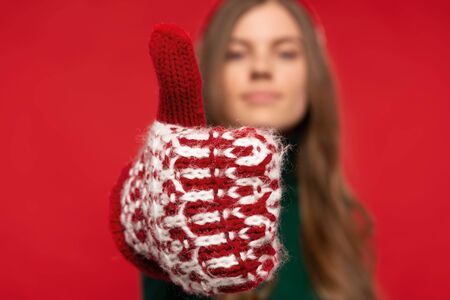 selective focus of woman in mitten showing thumb up isolated on red background. Christmas concept