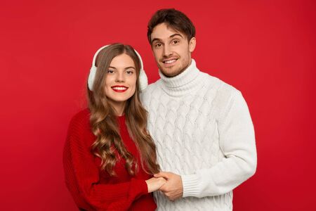 smiling young couple holding hands isolated on red background. Christmas conceptの写真素材