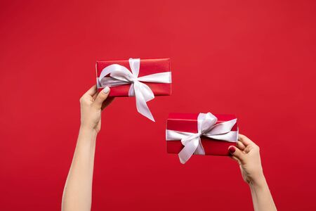 cropped view of woman holding wrapped Christmas presents with white ribbons isolated on red background. Christmas conceptの写真素材