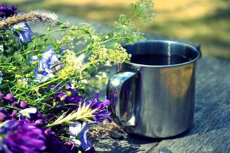 cup of tea standing on a table with blooming flowers, filterの写真素材