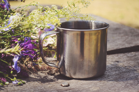 Metal mug on a table with beautiful blooming flowers, filter,の写真素材