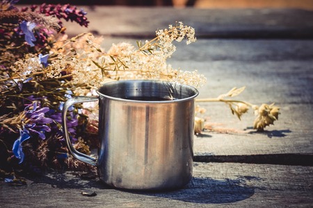 steel mug of tea on the table and fresh flowers, filterの写真素材