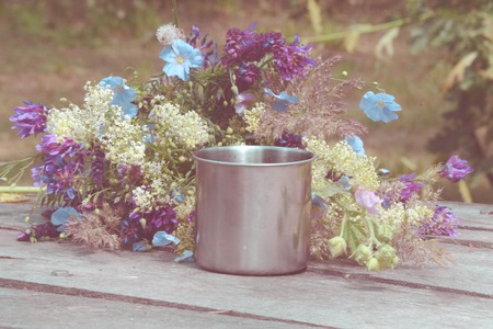 steel mug on a table with a bouquet of flowers, filterの写真素材