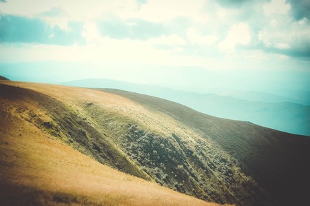 the sun shines on part of the field at the top of the mountainの写真素材