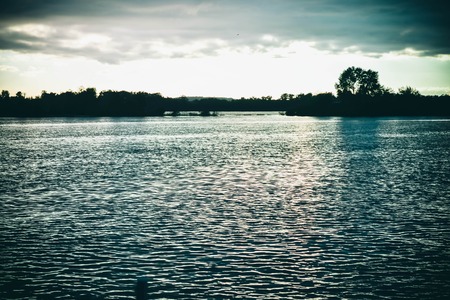 dark clouds at sunset, sunrise above the water surface, filterの写真素材