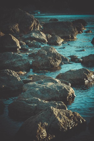 Large stones in the water near the shore, filterの写真素材