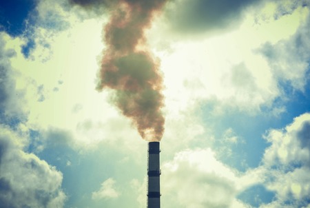 technogenic contrasting background tip of the pipe with smoke sky with cloudsの写真素材