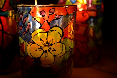 glass candle holder painted stained glass paints with a burning candle insideの写真素材