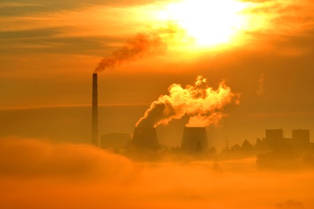 plant with pipes and smoke at sunset dawn. Red, orange cityscape. Landscape with smoke and morning fog. Contrasting the dark silhouette of the plantの写真素材