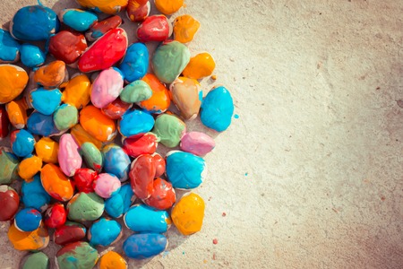 Colored stones colored paints in different colors lie on a flat surface. Second half empty. Close-upの写真素材