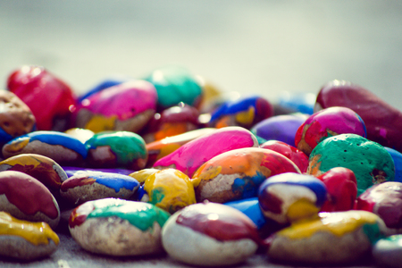 Many small pebbles covered with multicolored paint lie on the surface close-upの写真素材