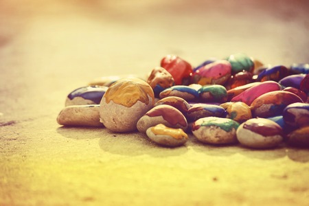 Many small pebbles covered with multicolored paint lie on the surface close-upの写真素材