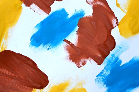 abstract background brush strokes yellow, brown, blue ink on white paper close-upの写真素材
