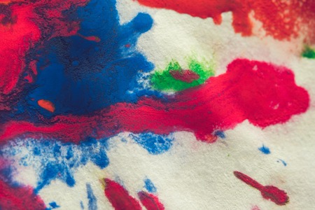 abstract spots splash of bright red, green, blue colors on white paper macro