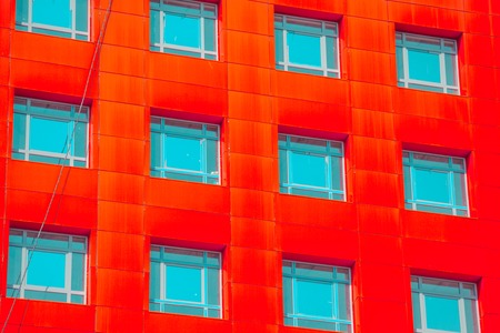 abstract facade of a modern building. Red square windows with blue glassの写真素材