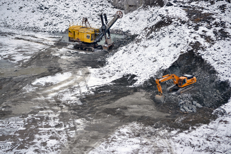big huge yellow excavator and Machine for breaking stones in a granite quarry in winterの写真素材
