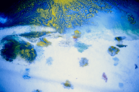 bursts of multicolored paints and mixed together white paper. Drawn splashes of paints of different colors on white surface. Blue, yellow, red, green color. Spreading spraying flow leak stream mixingの写真素材
