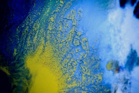 bursts of multicolored paints and mixed together white paper. Drawn splashes of paints of different colors on white surface. Blue, yellow, red, green color. Spreading spraying flow leak stream mixingの写真素材