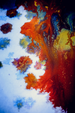 bursts of multicolored paints and mixed together white paper. Drawn splashes of paints of different colors on white surface. Blue, yellow, red, green color. Spreading spraying flow leak stream mixingの写真素材