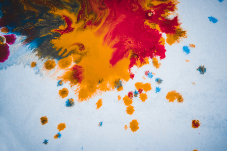 divorces and paint drips red, orange, yellow, blue blurred abstract background on a white paper background plane surface close-up macro with filter toning effectの写真素材