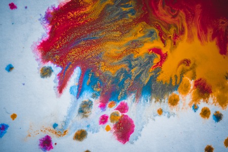 divorces and paint drips red, orange, yellow, blue blurred abstract background on a white paper background plane surface close-up macro with filter toning effectの写真素材