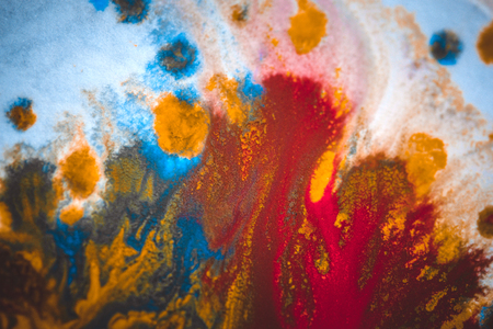 divorces and paint drips red, orange, yellow, blue blurred abstract background on a white paper background plane surface close-up macro with filter toning effectの写真素材