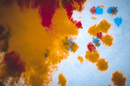 divorces and paint drips red, orange, yellow, blue blurred abstract background on a white paper background plane surface close-up macro with filter toning effectの写真素材