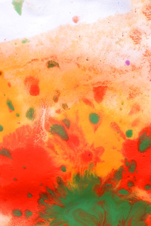 Warm abstract background red, yellow, orange ink spot swith green drops on white paperの写真素材