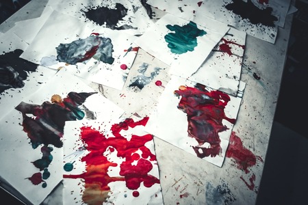 Many red colored blots on white paper with streaks. Abstract creative spots of paint on a white background. Red bright colors. Stained-spattered tableの写真素材