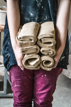 Master potter girl holding a many cut and twisted layers roll of clay pieces. Creative studio potter. Workplace wizard Crock potteryの写真素材
