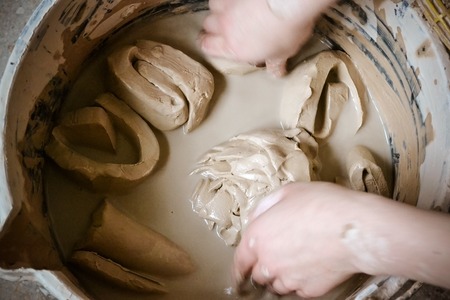 clay pieces soak in water in a bucket top view close-up. Creative studio potter. Workplace wizard Crock potteryの写真素材