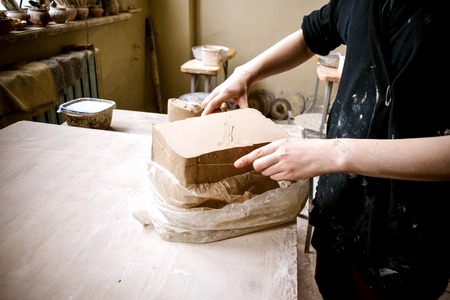 White clay preparation for work. Cutting layers of clay pieces for sculpting in the workshop of a potter Close-up. Twisted clay sheets on the old wooden table in pottery. Ukraineの写真素材