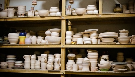 many different pottery standing on the shelves in a pottery workshop. Low lightの写真素材