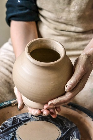 Potter holds more crude to the firing of white clay jug. Sculptor sculpts pots products from white clay. Master keeps on empty hands open earthen vessel. Workshop pottery.Ukraine, national traditionsの写真素材