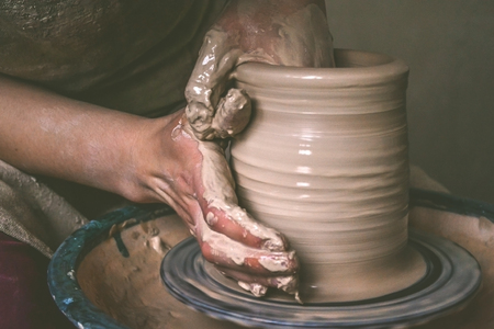 Creating a jar or vase of white clay close-up. Master crock. Man hands making clay jug macro. The...