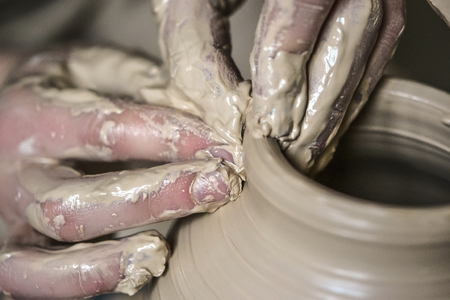 Hands in the clay macro. Making Crock crude wet close-up. Man hands making clay jug macro. The sculptor in the workshop makes a jug out of earthenware closeup. Vase of white clay crude wet closeup,の写真素材