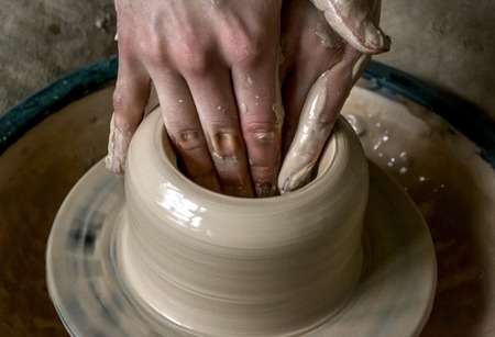 Girl sculpts in clay pot closeup. Modeling clay close-up. Caucasian man making vessel daytime of white clay in fast moving circle. Art, creativity. Ukraine, cultural traditions. Hobbiesの写真素材