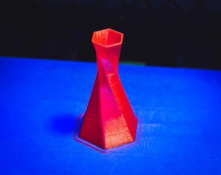 Model is printed on the 3D printer close. 3D printer printing object red color on the basis of blue and black background close-up. Modern 3d printing technologyの写真素材