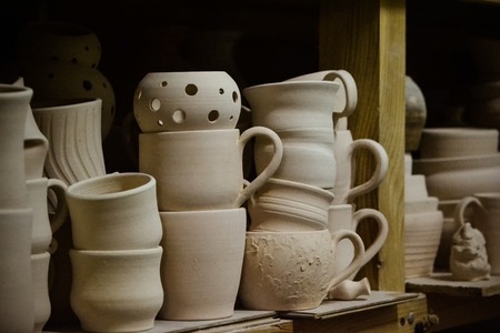 Bright pottery. Many white, not painted clay pottery standing on wooden shelvesの写真素材
