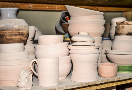Bright pottery. Many white, not painted clay pottery standing on wooden shelves