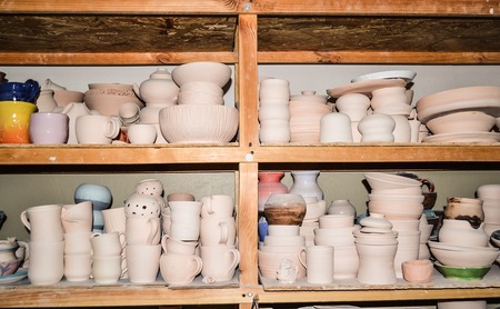 Bright pottery. Many white, not painted clay pottery standing on wooden shelvesの写真素材