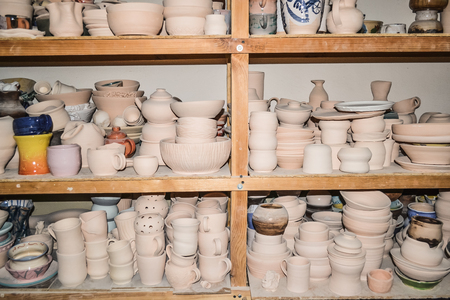 Bright pottery. Many white, not painted clay pottery standing on wooden shelvesの写真素材