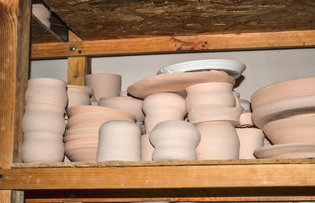 Bright pottery. Many white, not painted clay pottery standing on wooden shelvesの写真素材