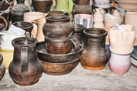 Clay dishes. Brown pottery standing on the dusty old desktopの写真素材